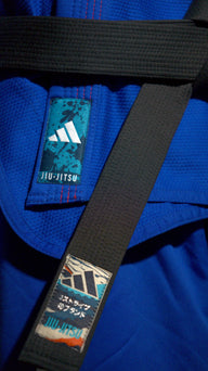 תקריב של חגורת ג׳יו ג׳יטסו שחורה של Adidas על חליפה כחולה