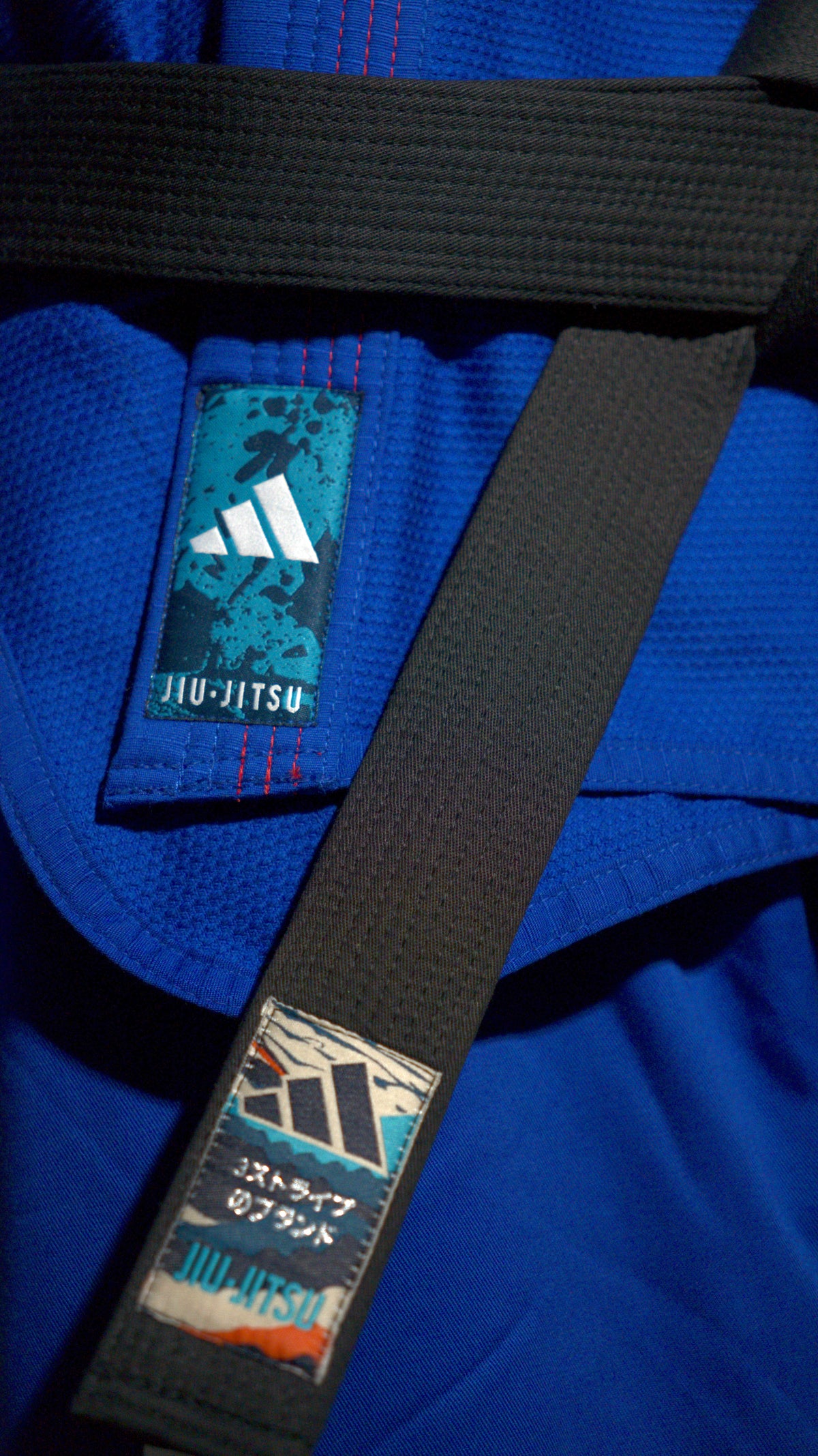 תקריב של חגורת ג׳יו ג׳יטסו שחורה של Adidas על חליפה כחולה