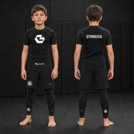 Child wearing the full branded Gymnasia short-sleeve No-Gi set with shorts over tights, front and back